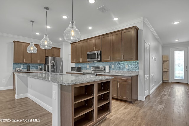 kitchen featuring visible vents, appliances with stainless steel finishes, ornamental molding, open shelves, and a sink