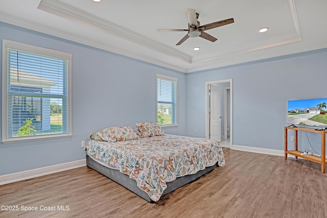 bedroom with ornamental molding, a tray ceiling, and wood finished floors