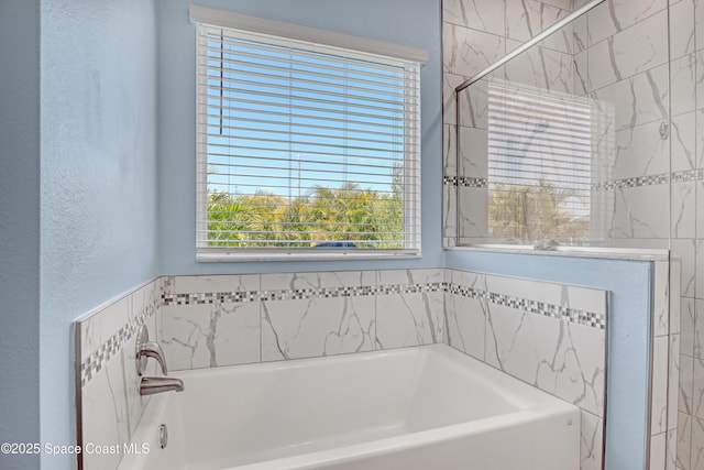 full bath with a garden tub and a textured wall