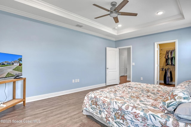 bedroom featuring crown molding, a raised ceiling, visible vents, wood finished floors, and baseboards