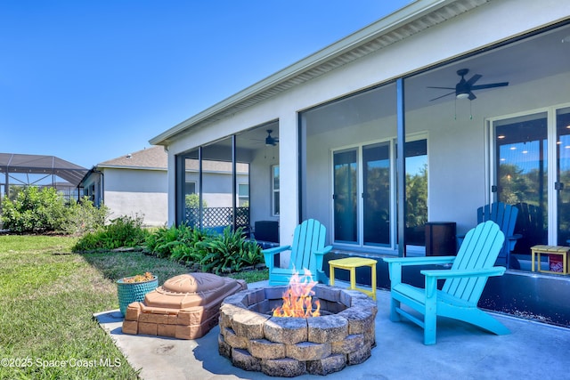 view of patio / terrace with a sunroom, ceiling fan, and a fire pit