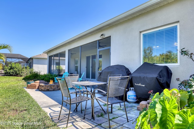 view of patio / terrace featuring a fire pit, a grill, and a sunroom