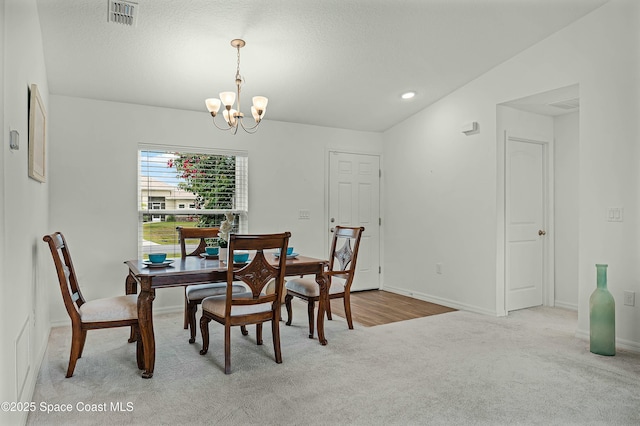 dining area with a chandelier, baseboards, visible vents, and light colored carpet