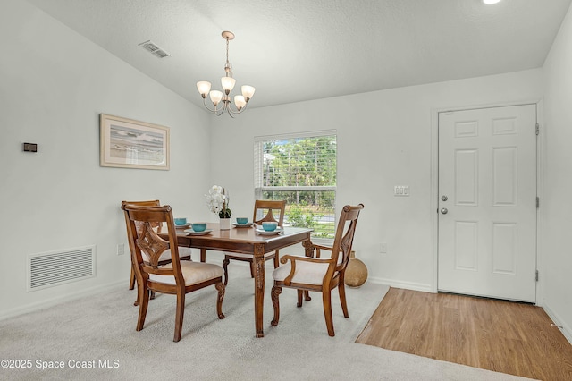 dining area with lofted ceiling, baseboards, visible vents, and a notable chandelier