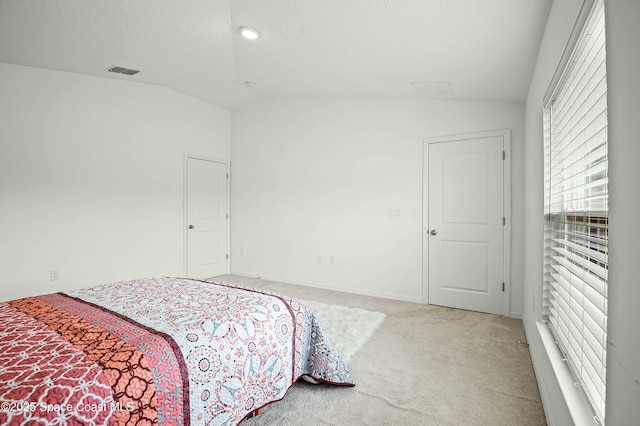 bedroom with carpet floors, visible vents, vaulted ceiling, and a textured ceiling