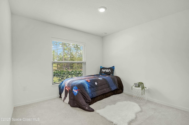 carpeted bedroom featuring a textured ceiling and baseboards