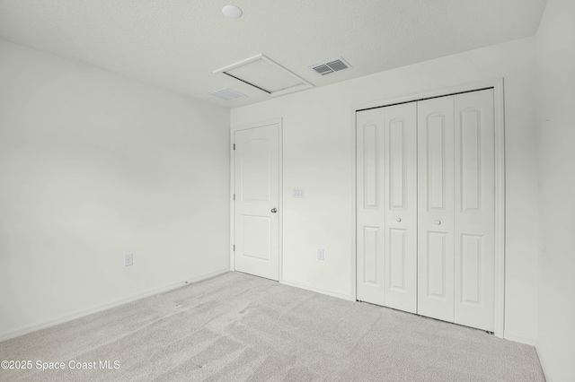 unfurnished bedroom featuring carpet, attic access, visible vents, and a textured ceiling