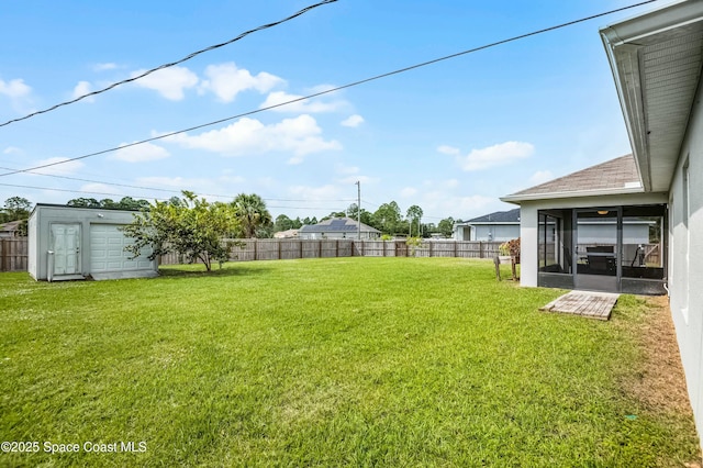 view of yard with an outbuilding, a shed, a fenced backyard, and a sunroom