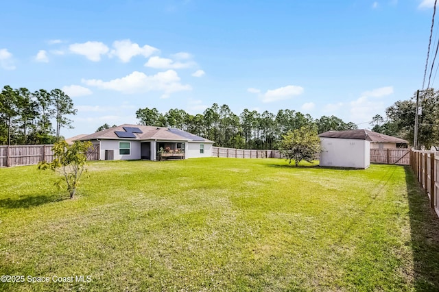 view of yard with a storage shed, a fenced backyard, and an outdoor structure