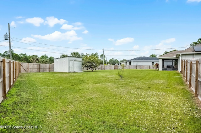 view of yard with a fenced backyard, a storage unit, and an outbuilding