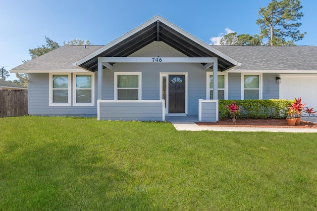 ranch-style house with roof with shingles, an attached garage, and a front lawn