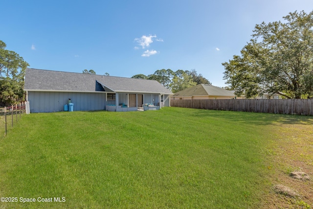 rear view of house featuring a fenced backyard and a lawn