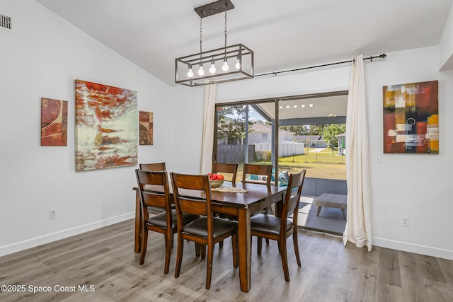 dining space with lofted ceiling, wood finished floors, visible vents, and baseboards