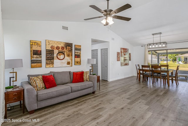 living area featuring ceiling fan, high vaulted ceiling, wood finished floors, visible vents, and baseboards