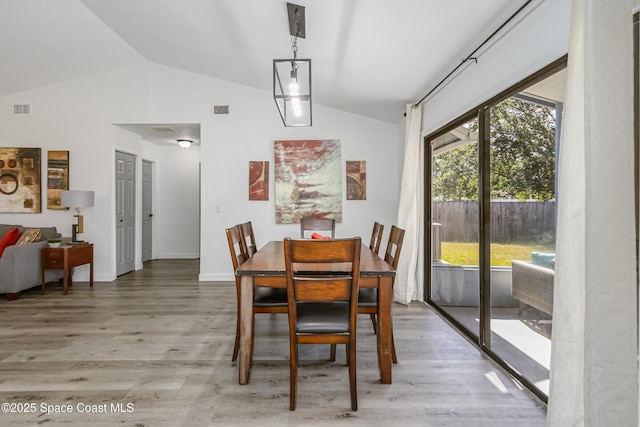 dining space with vaulted ceiling, light wood finished floors, and visible vents