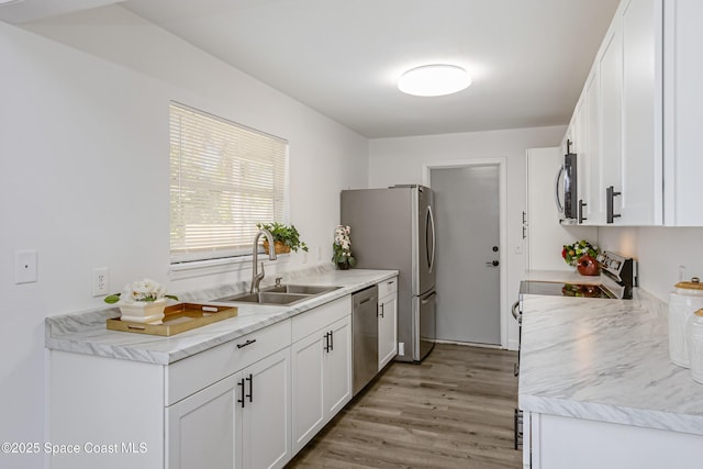 kitchen featuring appliances with stainless steel finishes, white cabinetry, a sink, and light wood-style flooring