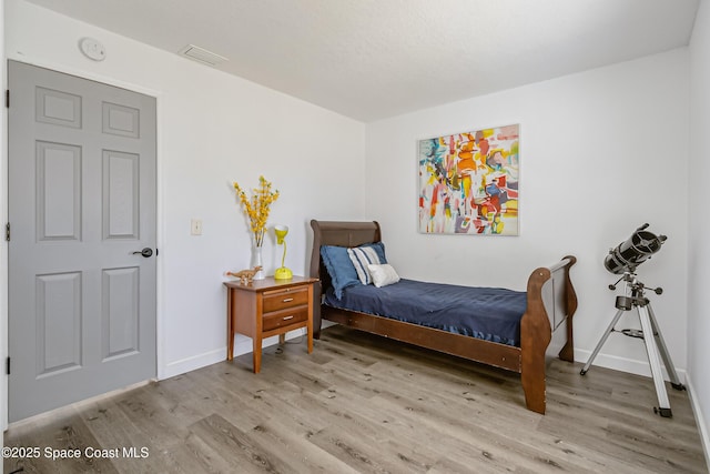 bedroom with light wood-style floors, baseboards, and visible vents