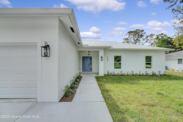 view of front of property with a front lawn, metal roof, an attached garage, and stucco siding