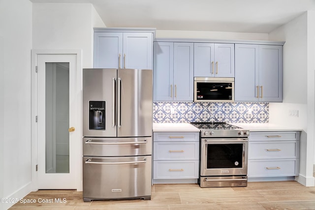 kitchen with stainless steel appliances, light countertops, light wood finished floors, and tasteful backsplash