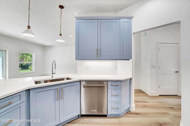 kitchen with hanging light fixtures, light wood finished floors, a sink, and light countertops