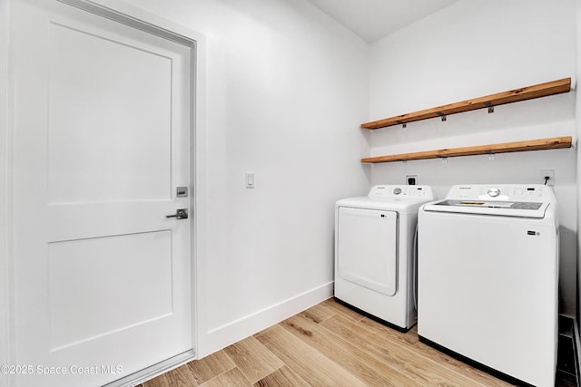 laundry room with baseboards, laundry area, washing machine and dryer, and light wood-style floors