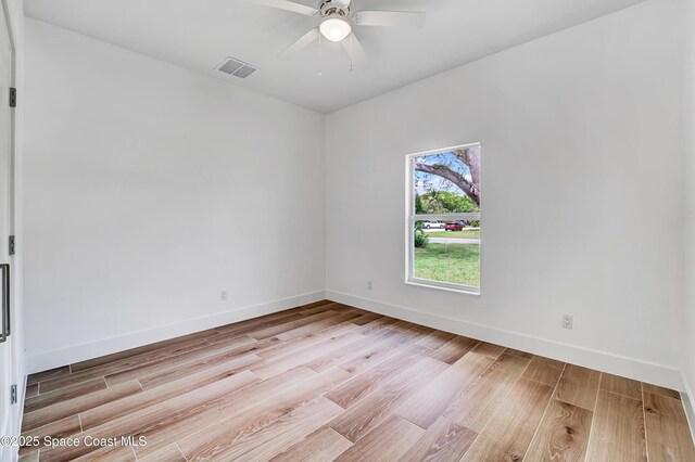 unfurnished room with light wood-style floors, visible vents, and baseboards