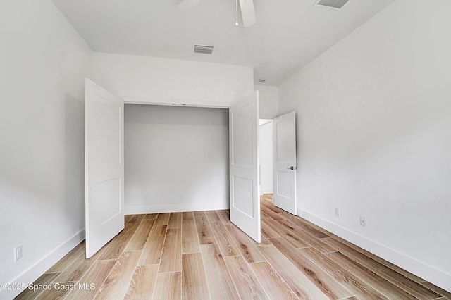 unfurnished bedroom with a closet, visible vents, a ceiling fan, light wood-type flooring, and baseboards