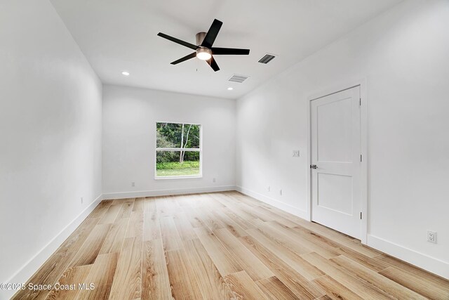 spare room featuring light wood-type flooring, visible vents, and baseboards