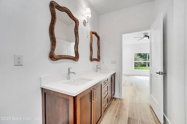 bathroom featuring double vanity, baseboards, a sink, and wood finished floors