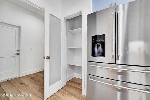 kitchen featuring stainless steel fridge, light wood-style flooring, and baseboards