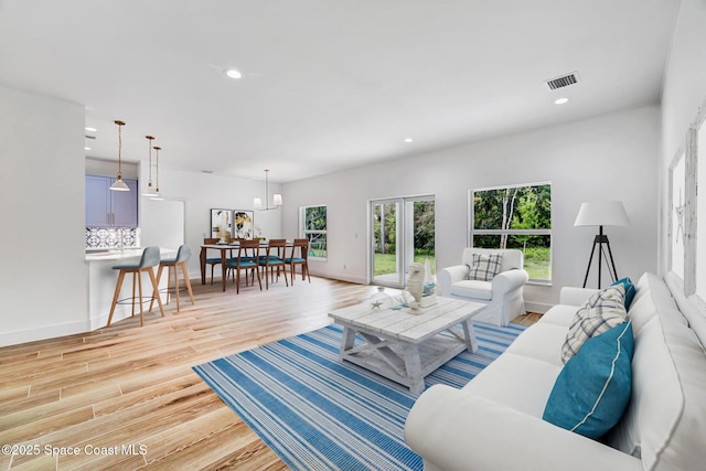 living room featuring baseboards, light wood-type flooring, visible vents, and recessed lighting