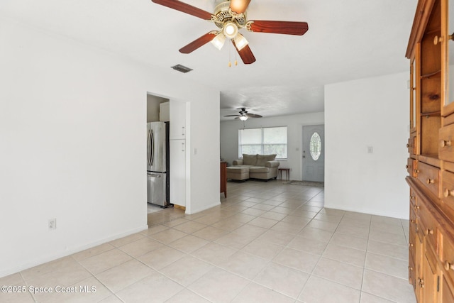 empty room featuring light tile patterned floors, ceiling fan, visible vents, and baseboards