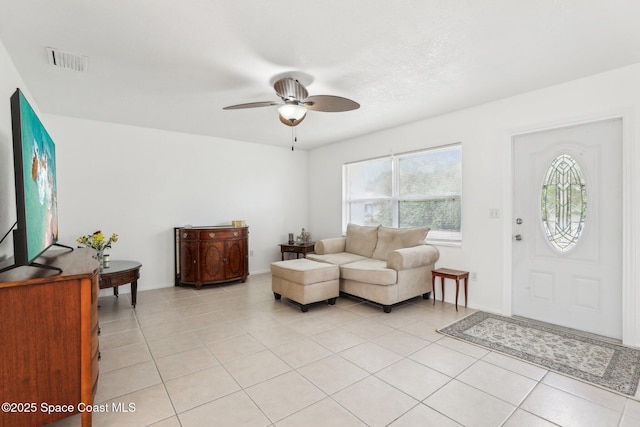 living room featuring light tile patterned floors, visible vents, and a ceiling fan