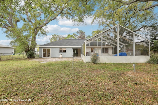 rear view of property featuring a lanai, fence, a lawn, and a patio