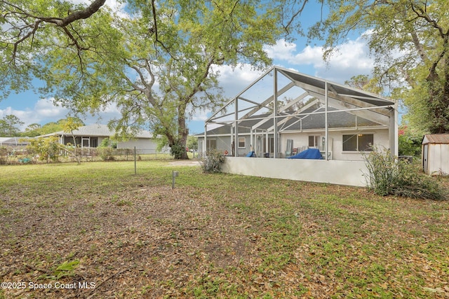 back of house with glass enclosure, fence, an outbuilding, and a yard