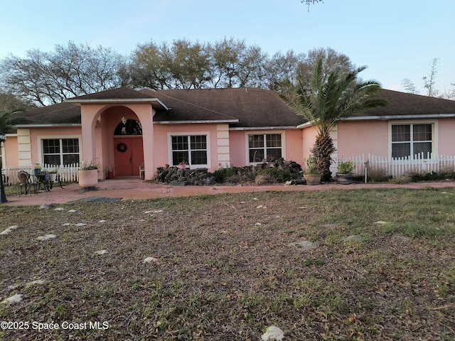 ranch-style house with a patio area, fence, a front lawn, and stucco siding