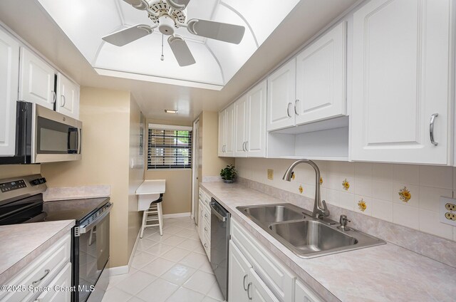 kitchen with white cabinetry, stainless steel appliances, a tray ceiling, and a sink