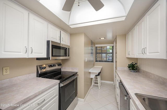 kitchen with baseboards, light countertops, white cabinets, stainless steel appliances, and a ceiling fan