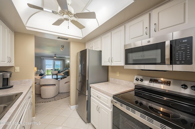 kitchen featuring visible vents, a tray ceiling, ceiling fan, stainless steel appliances, and white cabinets