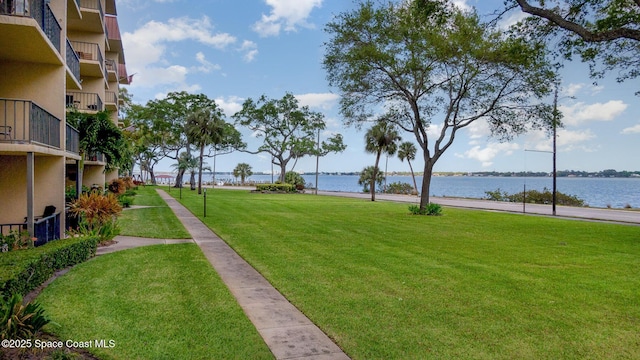view of property's community with a lawn and a water view