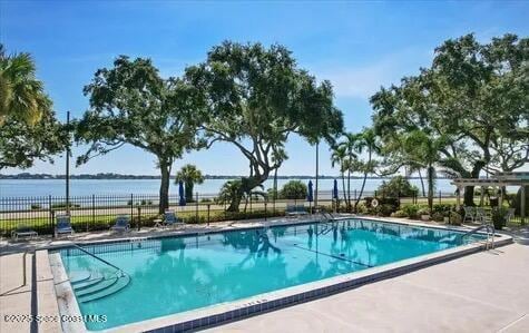 pool with a water view, a patio, and fence