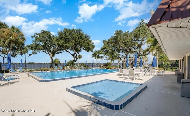 pool with a patio area, a community hot tub, and fence