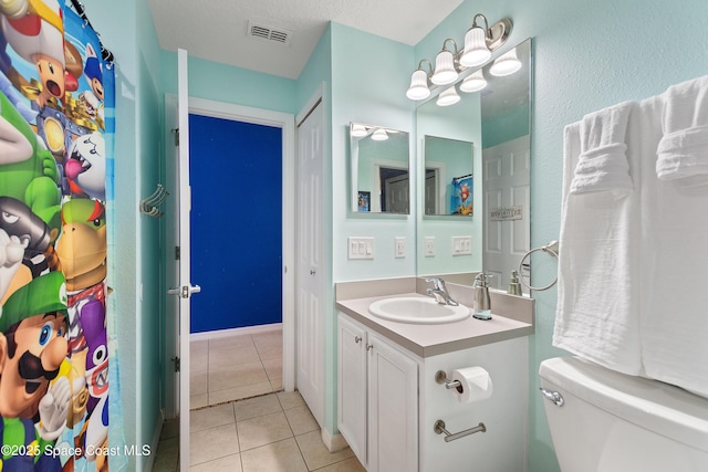 bathroom with toilet, vanity, tile patterned flooring, and visible vents