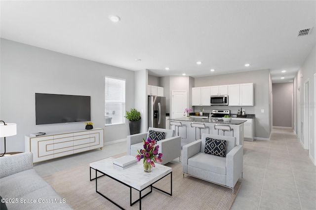 living area featuring light tile patterned floors, baseboards, visible vents, and recessed lighting