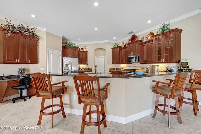 kitchen featuring glass insert cabinets, crown molding, decorative backsplash, a peninsula, and stainless steel appliances