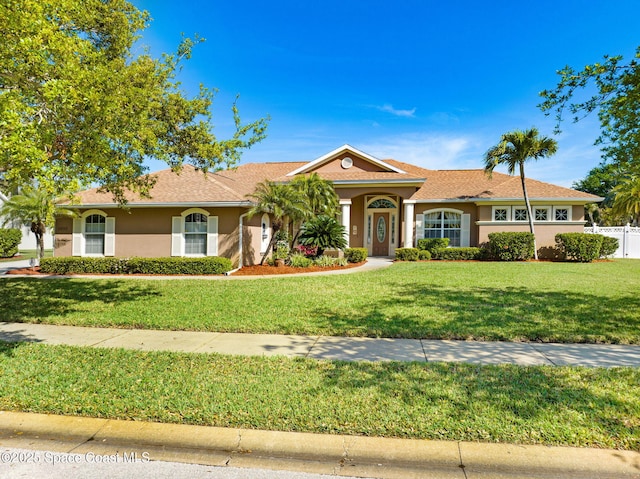 ranch-style house with a front yard, fence, and stucco siding