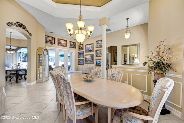 dining room featuring light tile patterned floors, arched walkways, a raised ceiling, a decorative wall, and a notable chandelier