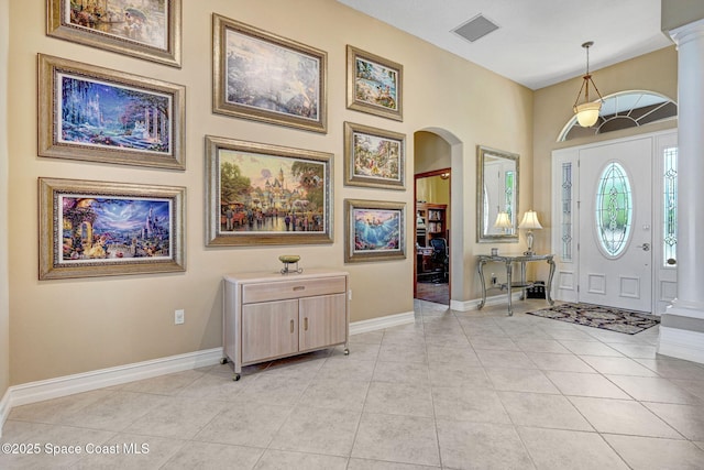 entrance foyer featuring light tile patterned floors, visible vents, arched walkways, and baseboards