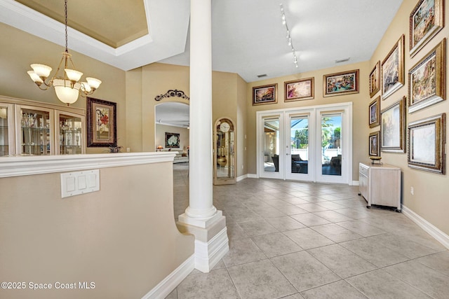 foyer entrance featuring track lighting, baseboards, light tile patterned floors, an inviting chandelier, and arched walkways