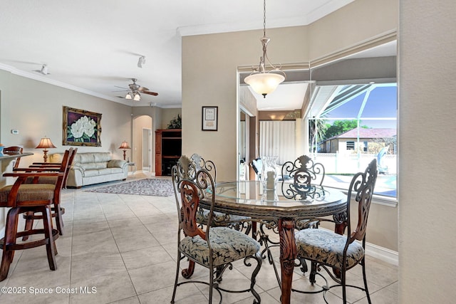 dining room with light tile patterned floors, a ceiling fan, arched walkways, and ornamental molding